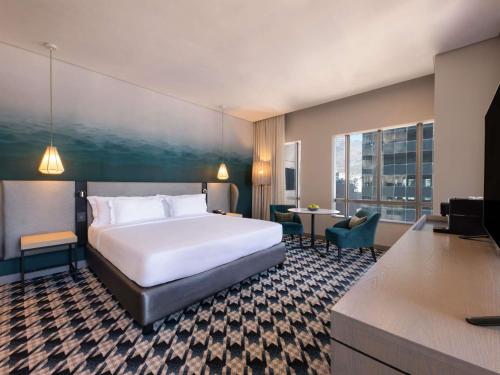 a hotel room with a large bed and a desk at Pullman Cape Town City Centre in Cape Town