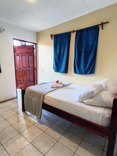 a bedroom with a large bed with blue curtains at Chale's House Hotel in San Juan del Sur