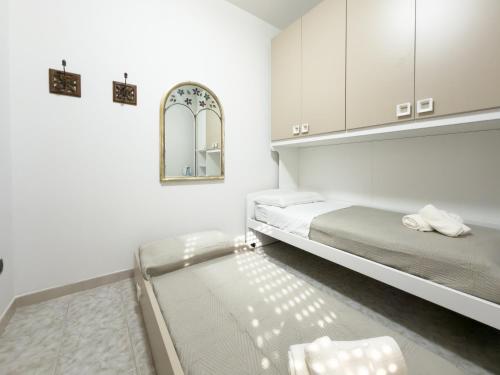 a white room with two beds and a mirror at Unit 120 in SantʼAgata di Militello