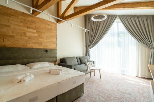 a bedroom with a bed and a couch and a chair at APLEND Aparthotel Litvor in Štrba
