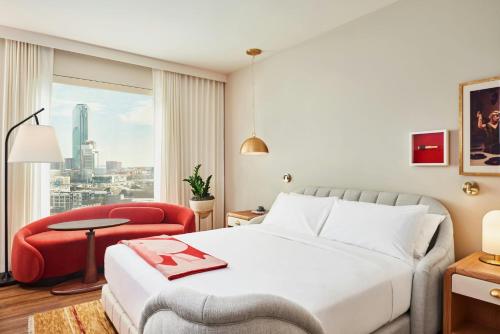 a hotel room with a bed and a red chair at Virgin Hotels Dallas in Dallas