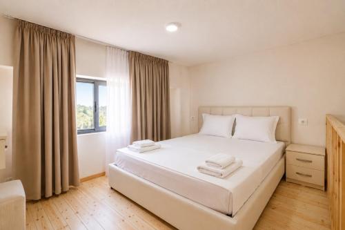 a bedroom with a white bed and a window at Vila Francesko in Ksamil