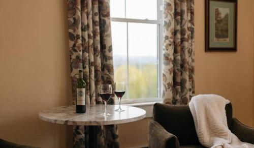 a table with two glasses of wine and a window at Mountain View Grand Resort & Spa in Whitefield