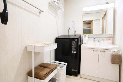 a small kitchen with a sink and a black refrigerator at Chillax Hida Takayama in Takayama