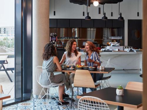 three women sitting at a table in a restaurant at Aparthotel Adagio Heidelberg in Heidelberg
