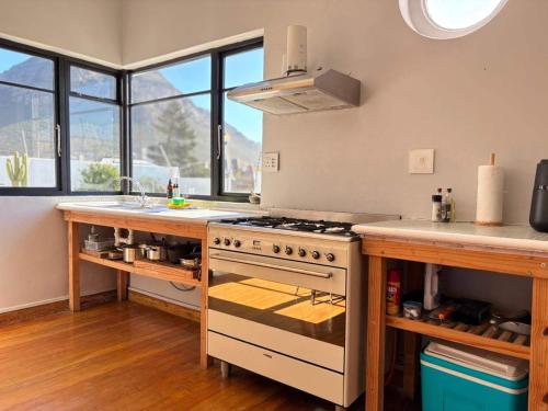 a kitchen with a stove and a counter with windows at Beach Paradise in Muizenberg