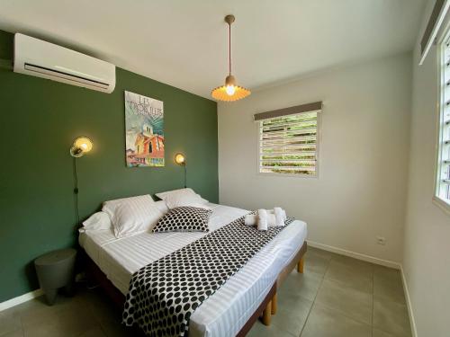 a bedroom with a bed with a black and white comforter at Villa APOLLINAIRE in Les Trois-Îlets