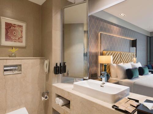 a bathroom with a sink and a bed and a mirror at Grand Mercure Agra - An Accor Brand in Agra