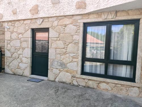 a stone building with a black door and windows at A casa do sal 