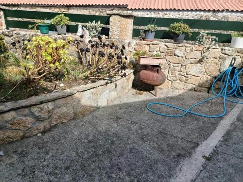 a vase with a hose next to a stone wall at A casa do sal 