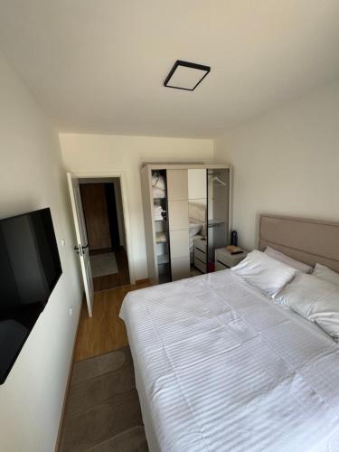 a bedroom with a white bed and a flat screen tv at Lovely apartmant Bar in Bar