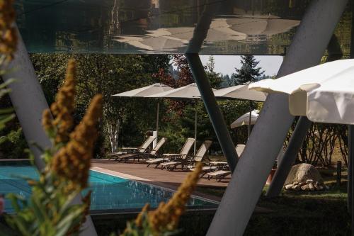 a row of lounge chairs and umbrellas next to a pool at Parkhotel Flora am Schluchsee in Schluchsee