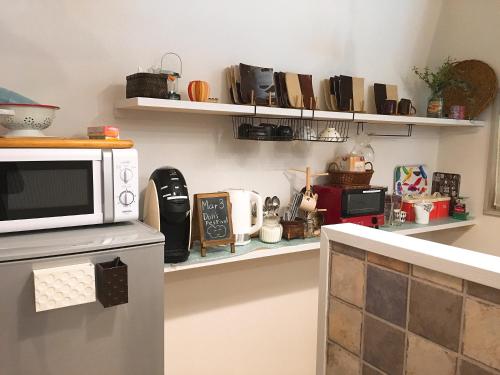 a kitchen with a microwave on top of a counter at Hiroshima Guesthouse HARU in Hiroshima
