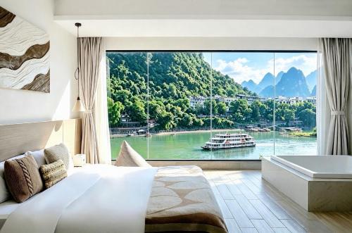 a bedroom with a large window with a boat in the water at Ruoli Yangshuo in Yangshuo