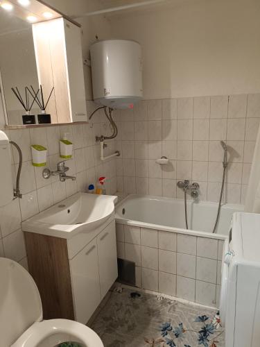 a bathroom with a sink and a tub and a toilet at Apartman Orhideja in Višegrad