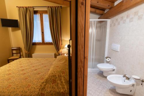 a bedroom with a bed and a bathroom with a toilet at Agriturismo Vigneto Vecio in Valdobbiadene