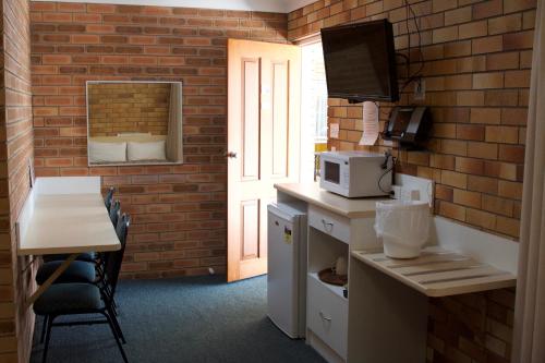 a room with a kitchen with a table and a microwave at Buckaroo Motor Inn in Warwick