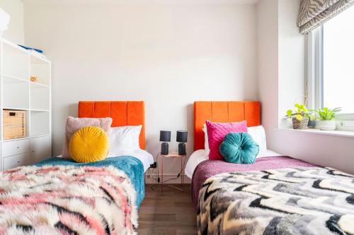 two beds with colorful pillows in a bedroom at Walpole Bay Sea Views in Margate