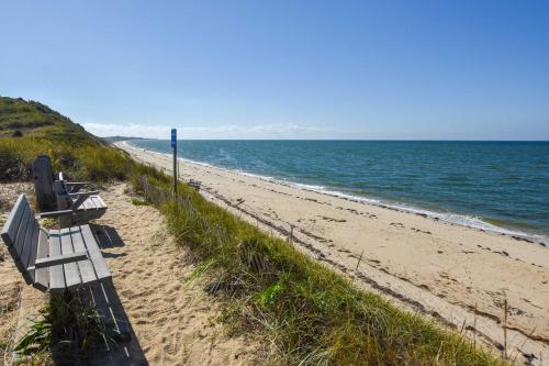 a row of benches sitting on a sandy beach at Beautiful backyard pool deeded beach rights in Truro
