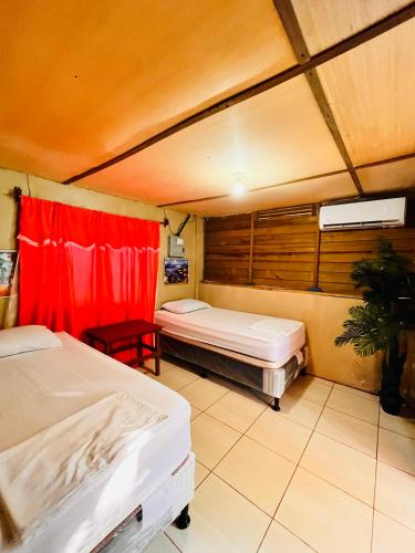 a bedroom with two beds and a red curtain at Bedrooms where Charlie in El Paredón Buena Vista