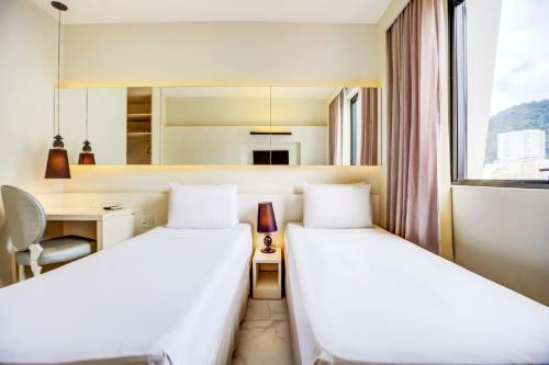 two beds in a hotel room with a desk at Aera Rio de Janeiro Copacabana in Rio de Janeiro