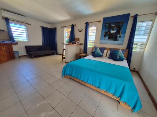 a bedroom with a blue bed and a couch at Terre et Mer - Studios - Ile Maurice in Rivière Noire