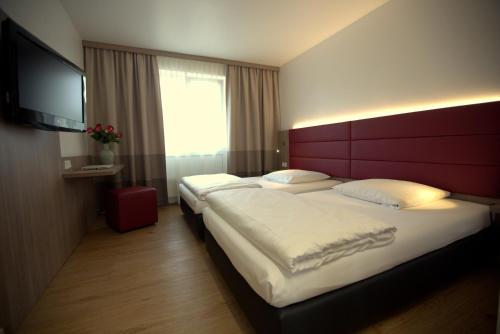 a hotel room with two beds and a flat screen tv at Airport Hotel Walldorf in Mörfelden-Walldorf