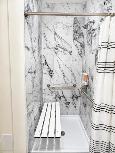 a bathroom with a marble shower with a bench at The Accessible Atom | Historic Main in St. Charles