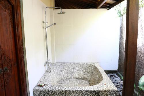 a bathroom with a shower with a stone tub at Lovina Beachhouse Villas in Lovina