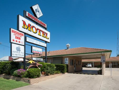a motel sign with a man standing in front of it at Buckaroo Motor Inn in Warwick