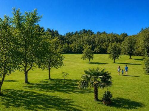 a group of people walking in a field with trees at La biche au bois piscine chauffee jacuzzi in Cazals