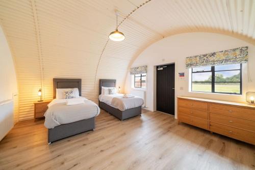 a large room with two beds and a window at Cultybraggan Hut 38 - Accessible in Comrie