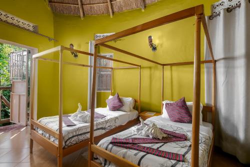 two beds in a room with yellow walls at Dream jet suites in Entebbe