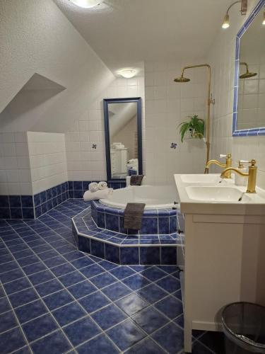a blue tiled bathroom with a tub and a sink at Villa Shakira in Zissersdorf