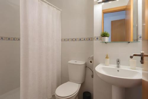 a white bathroom with a toilet and a sink at El Rincón Sevillano in Gerena