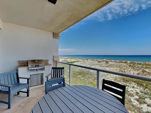 a balcony with a table and chairs and the beach at Beach Club #206A in Pensacola Beach