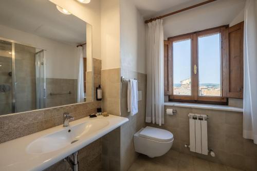 a bathroom with a sink and a toilet and a window at Relais Cloister Pienza in Pienza