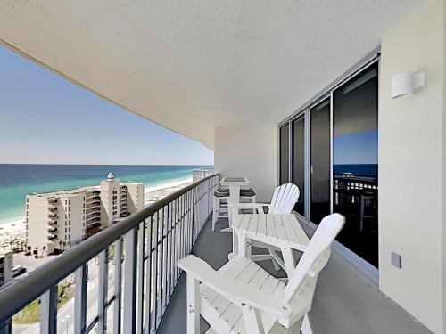 a balcony with white chairs and a view of the ocean at Emerald Dolphin #1630 in Pensacola Beach