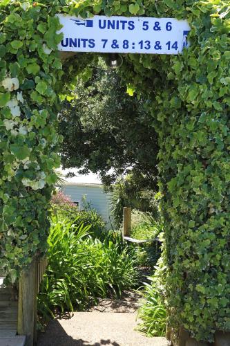 an archway with a sign in a garden with plants at Waiheke Island Motel in Ostend