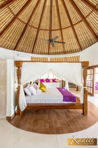 a bedroom with a bed in a straw roof at Villa Kaaiti in Uluwatu