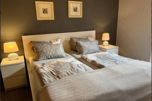 two beds in a bedroom with two lamps on tables at Ferienwohnung 2 Gemutlich & komfortabel im Erdgeschoss in Borkum