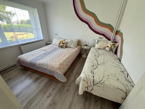 a bedroom with two beds and a rainbow on the wall at Rene Stay Naisiai in Naisiai