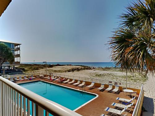 a swimming pool with lounge chairs and the beach at Driftwood Towers #1F - Palm View in Gulf Shores