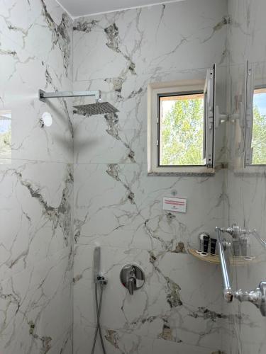 a white marble bathroom with a shower with a window at Lexhulo Room's in Domje