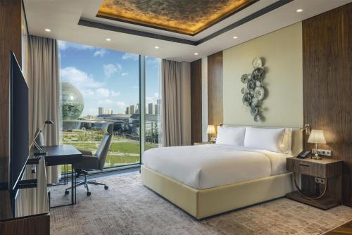 a bedroom with a bed and a desk and a window at Hilton Astana in Astana