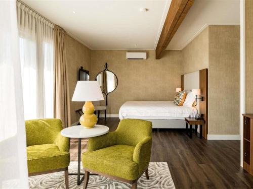 a bedroom with a bed and two chairs and a table at Hotel Ter Zand - Handwritten Collection in Burgh Haamstede