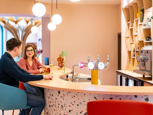 a man and a woman sitting at a bar at Ibis Styles Strasbourg Centre République in Strasbourg