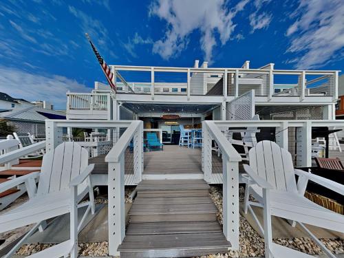 a boardwalk leading to a beach house with white chairs at Tiki Tango Hideaway in Panama City Beach