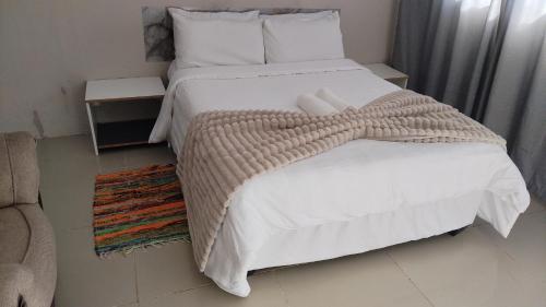 a bedroom with a large bed with white sheets and pillows at NGEBE Lodge jozini in Jozini