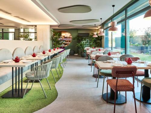 a restaurant with tables and chairs and windows at Ibis Styles Madrid Airport Valdebebas in Madrid